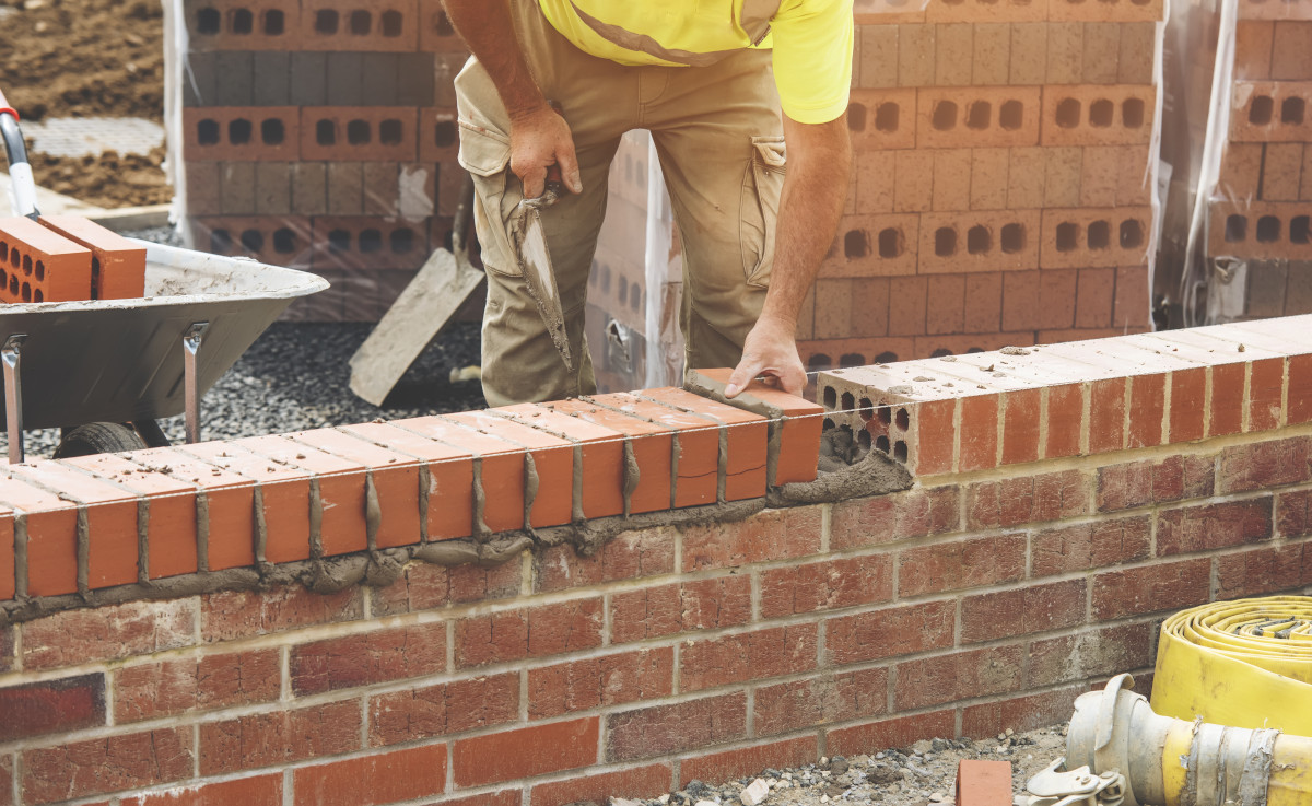 builder laying bricks on a wall