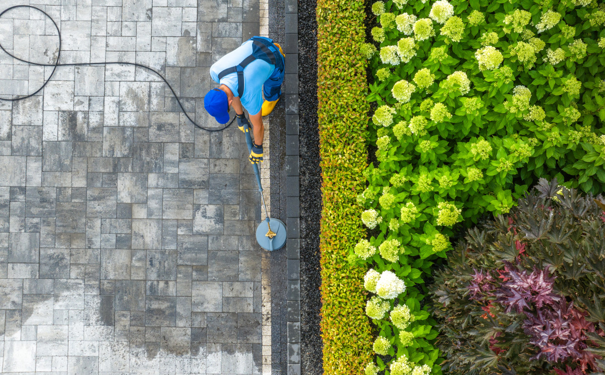 Aerial View of Worker with a Pressure Washer, jet washing a residential driveway