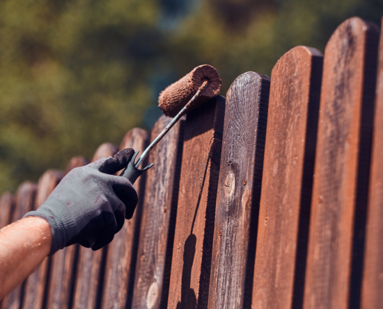 A hand painting a picket fence