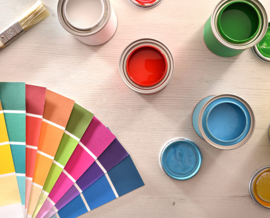 Colourful paint pots open and colour palette on white table for renovation of materials. Top view. Horizontal composition.