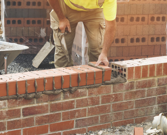 builder laying bricks on a wall